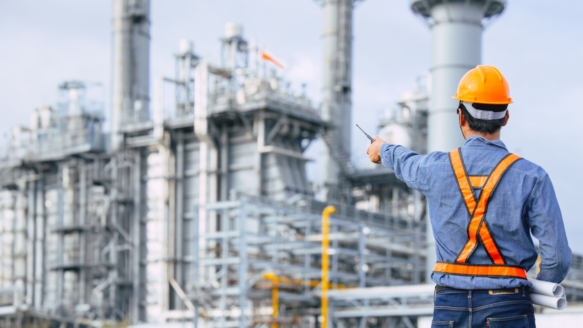 Petroleum Refinery industry engineer male working against oil and gas power industrial factory. Petrochemical power plant industry professional worker.