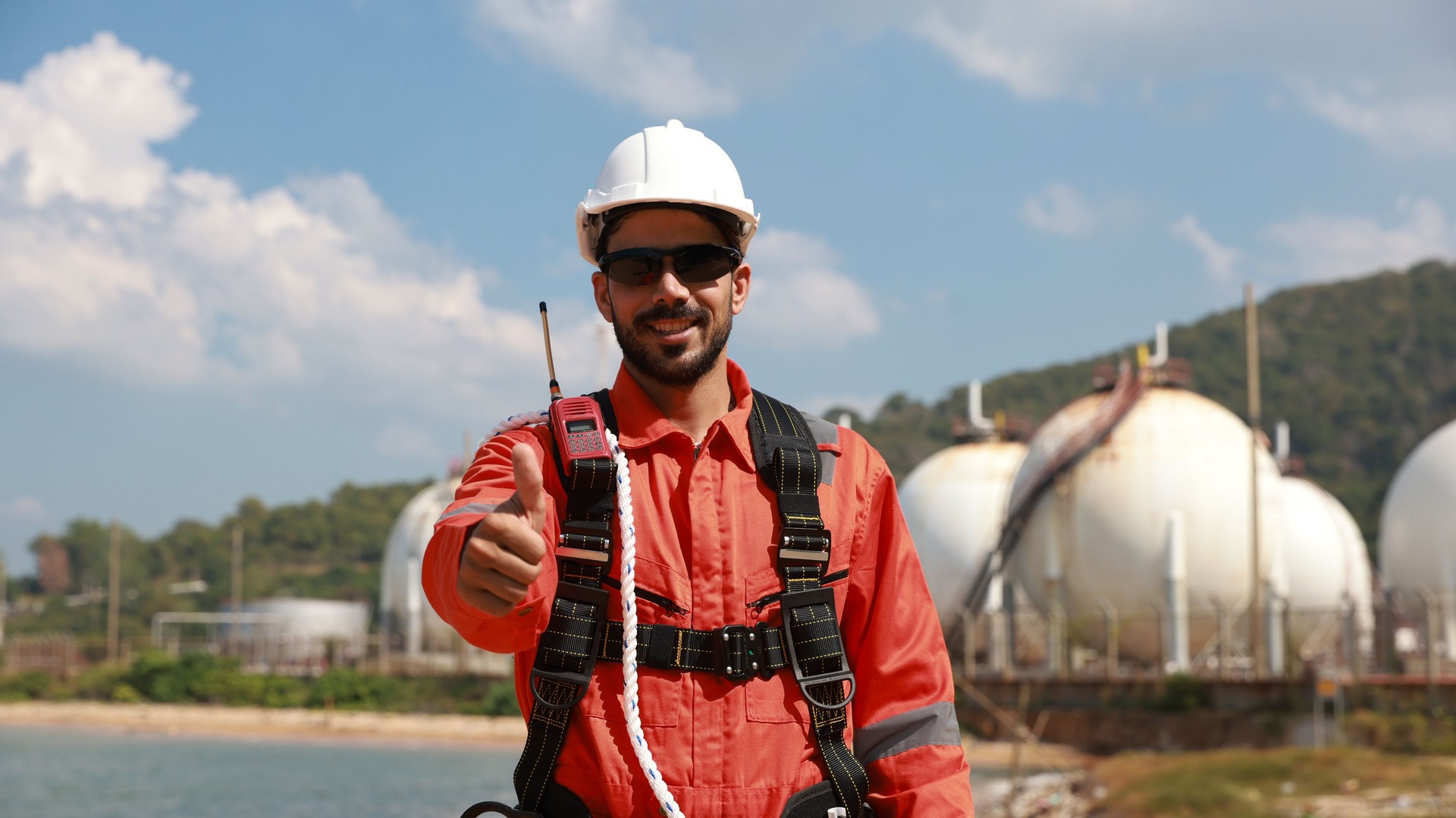 Portrait of smart engineer with safety uniform and harness equipment at the petrochemical site